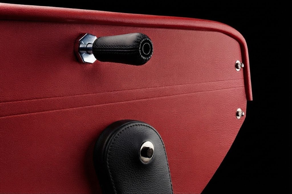 Poignée noire et chromée sur le flanc d'un baby-foot en cuir rouge, sur fond noir