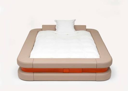 Le lit Bumper Bed de Marc Newson, vu de face : un cadre en cuir beige entouré d'un bandeau orange