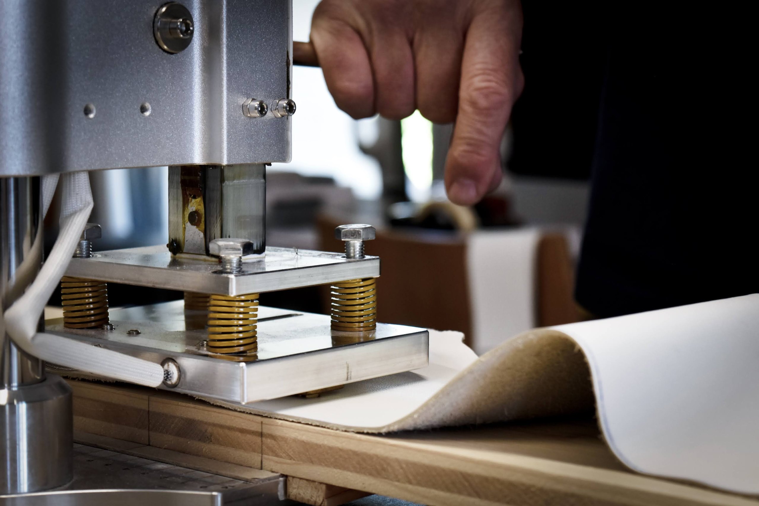 Une main presse une machine sur un cuir blanc