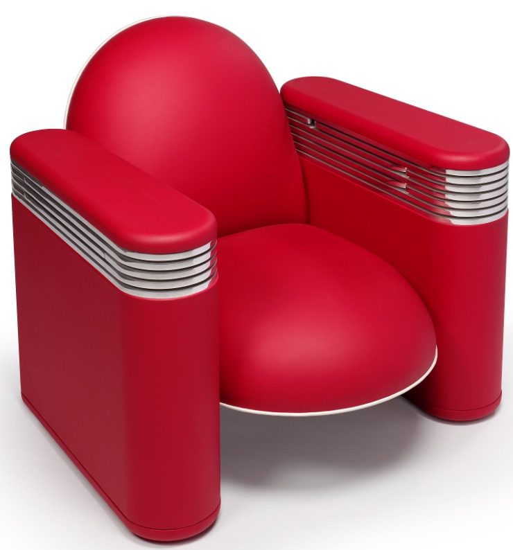 Un fauteuil en cuir rouge, vu de trois quarts, avec des anneaux d'aluminium aux accoudoirs