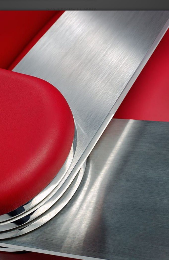 Une lame d'aluminium poli sortant d'un accoudoir en cuir rouge